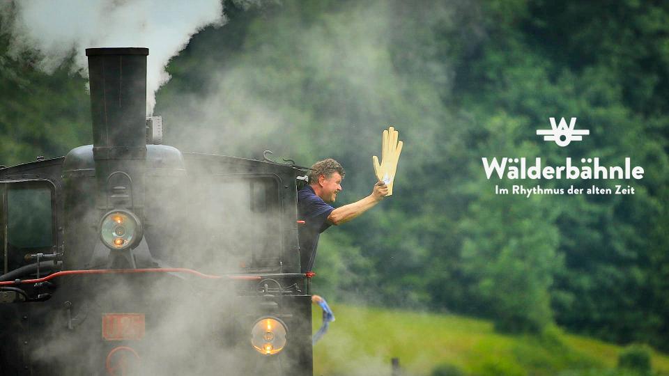 Lokführer winkt aus dem Führerstand der Dampflok
